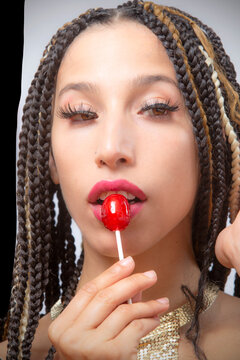 Lips of beautiful young Latina touching a red candy pop.