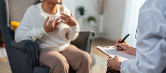 Asian caregiver nurse examine and listen to senior stress woman patient.  - obrazy, fototapety, plakaty