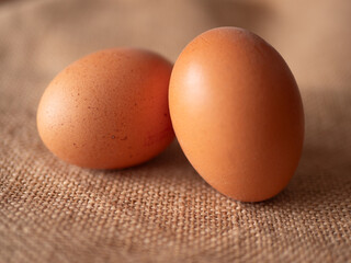 Two Fresh Brown Eggs on Textured Burlap Background