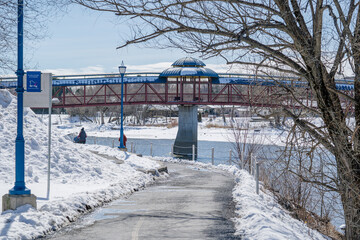 Fototapeta premium Bridge crossing a frozen river in a sunny winter day