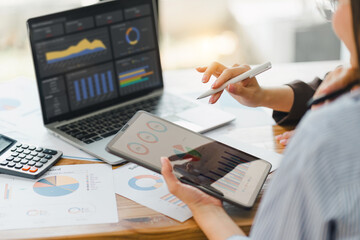 Two colleagues engaged in business analytics, using digital tablets over financial charts. Colleagues Collaborating with Tablets on Business Analytics.