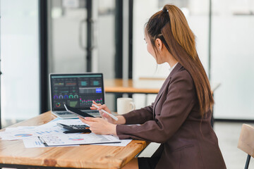 Professional businesswoman examines complex financial data on a laptop screen, with analytical...
