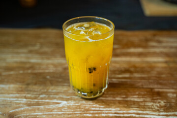 Fresh Look Drink in Yellow Color with Passion Fruit Seeds sinks to the bottom of the glass. Served on the Wooden Table