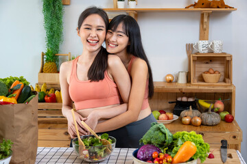 Asian couple of same sex marriage hugging each other while cooking healthy salad together in kitchen during pride month to promote equality and differences of homosexual and discrimination