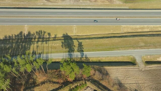 Overhead view of the S6 expressway in Pomerania near Gdynia, Poland, showcasing the linear stretch of road flanked by the stark silhouettes of trees