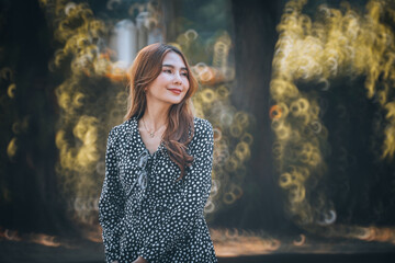 A woman in a stylish polka dot dress stands amidst a dreamy forest backdrop, looking away...