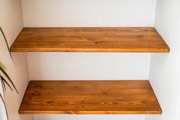 three empty wooden shelves on a white wall