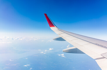 View from the airplane window at a beautiful cloudy sky and the airplane wing