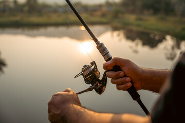 Close-up shot hand rotation with reel of fishing rod as a leisure activity during his vacation at...