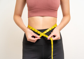Close up woman measuring her waistline with measure tape. Weight loss diet session. Woman in...
