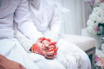 Young married couple holding hands, ceremony wedding. Malay wedding reception.