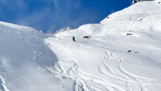 Early season deep powder fresh snow snowboarders snowboarding carve turning Stubai glacier ski resort Austria Alps October November deep blue clear skies white contrast fresh tracks follow pan