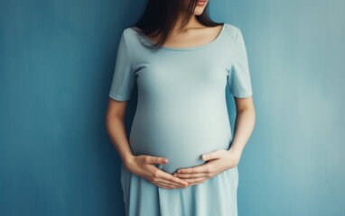 Pregnant woman holding her belly in blue dress