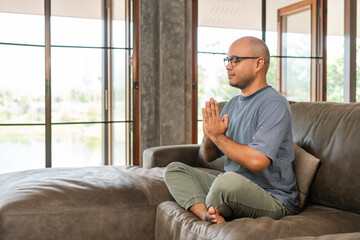 Asian man is meditation feel refreshed and relaxed on sofa in living room. Great pleasure handsome...