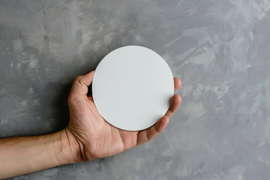 Hand Holding Round Blank White Sticker Mock Up Isolated On Gray. Sticker Mockup Holder. Empty Paper Clue Remnder Hold In Hands. Arm Sticking Round Sticker.