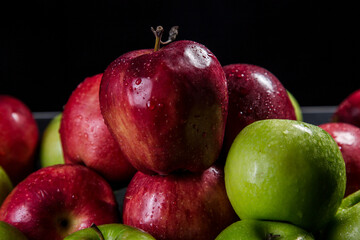 Red and green apples, black background