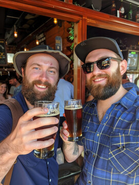 Two regular looking guys toasting their pints of ale at a local pub