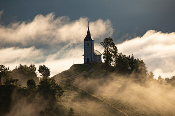 Jamnik, Slovenia - Magical foggy golden summer sunrise at Jamnik St.Primoz church.