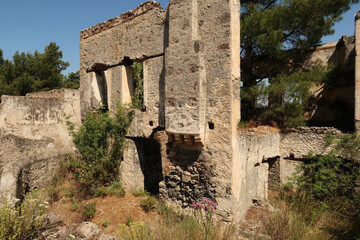 Leftover exterior wall of one of the houses in the abandoned village of Kayaköy with chimney,...