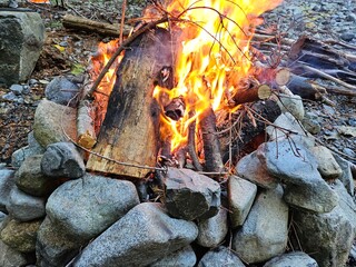 Flames of wood fire in the campground in stone fire pit in the forests of Washington State with a beautiful glow and smoke 