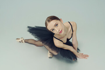 portrait of a ballerina in a black tutu lying on the floor leaning on her hands top view