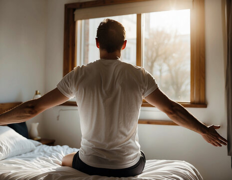 An early wake-up man sitting on the bed with a warm sunshine through the window
