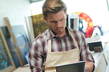 shoemaker using digital tablet in workshop