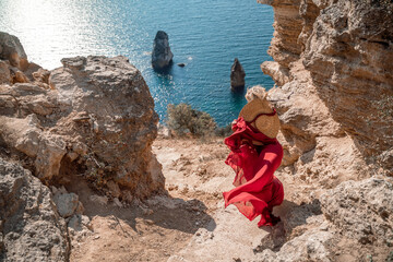 From behind, a woman is seen in a red flying dress fluttering in the wind. In a straw hat, walking...