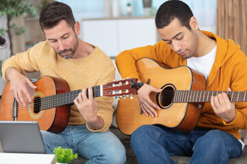 two focused men playing duet on accoustic guitars