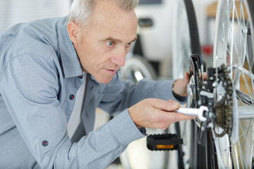 senior man repairing bicycle at home