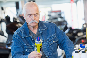 senior man looking at automobile lubricant spray