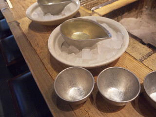 Sake cups and decanter in ice cubes on wooden table next to irory fireplace 