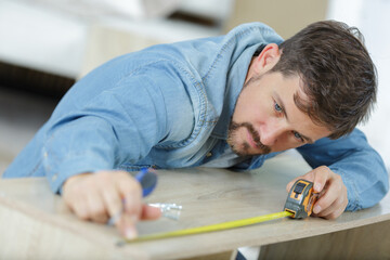 young man using tape measure for measuring a wood board