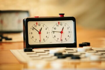 A board with checkers and clock on the table - obrazy, fototapety, plakaty