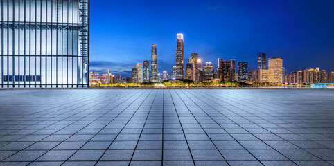 Empty square floor and glass wall with modern city buildings at night in Guangzhou. panoramic view.