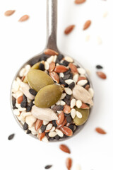 Mixed seeds sunflower, black and white sesame, flax and pumpkin in iron spoon on white background. Close-up