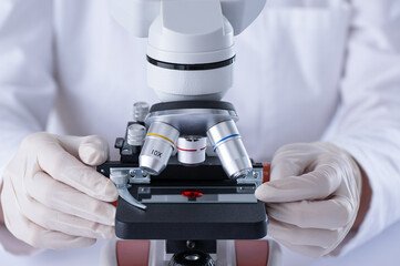 Scientist researching blood sample by microscope in laboratory closeup. Blood DNA test.