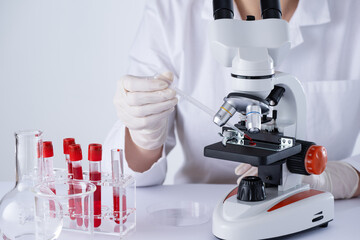A scientist is using a microscope to examine a blood sample. Test tubes with blood in laboratory. Blood DNA test. - 775619426