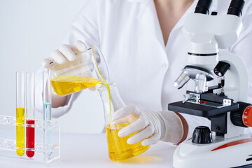Scientist researching in laboratory with hemp CBD oil. Woman working in laboratory with oil extract and microscope. - 775619482