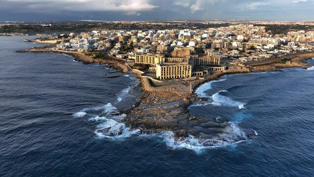 Drone shot landscape view of Abandoned Jerma Palace Hotel in Marsaskala, sunrise time, Malta.