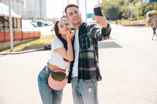 Smiling beautiful woman and her handsome boyfriend. Woman in casual summer clothes. Happy cheerful family. Female having fun. Sexy couple posing in the street at sunny day. Take selfie