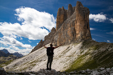 Stunning view of a tourist enjoying the view of the Tre Cime Di Lavaredo, Dolomites, Italy. - obrazy, fototapety, plakaty
