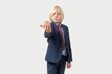 Portrait of a boy in a business suit and tie showing inviting gesture with his hand.