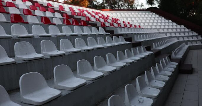 Empty seats in stadium and white plastic seats in stadium without spectators and fans. Stadium closures