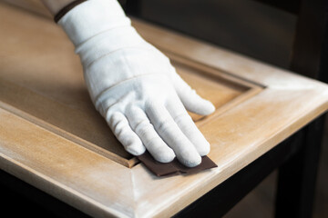 Person remonier worker sands a wooden product, kitchen facade with a sandpaper