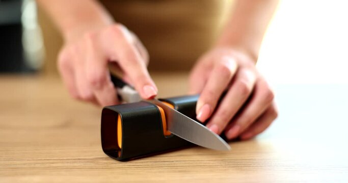 Man holds knife in hands in the kitchen and process of sharpening knives. Stainless steel knife sharpener