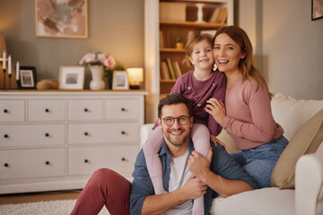Happy family with little daughter sitting on sofa in living room