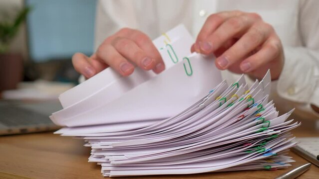Businessman searching documents lying on table, business report papers, important financial documents close up. Male Businessman working at home office with online trading market finance digital data