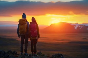Poster Couple of tourists enjoying beautiful sunset over Icelandic landscape during their trip to Iceland. © Ekaterina Pokrovsky