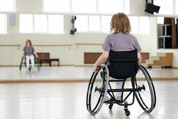 Selective focus rear view shot of unrecognizable young woman with disability in wheelchair...